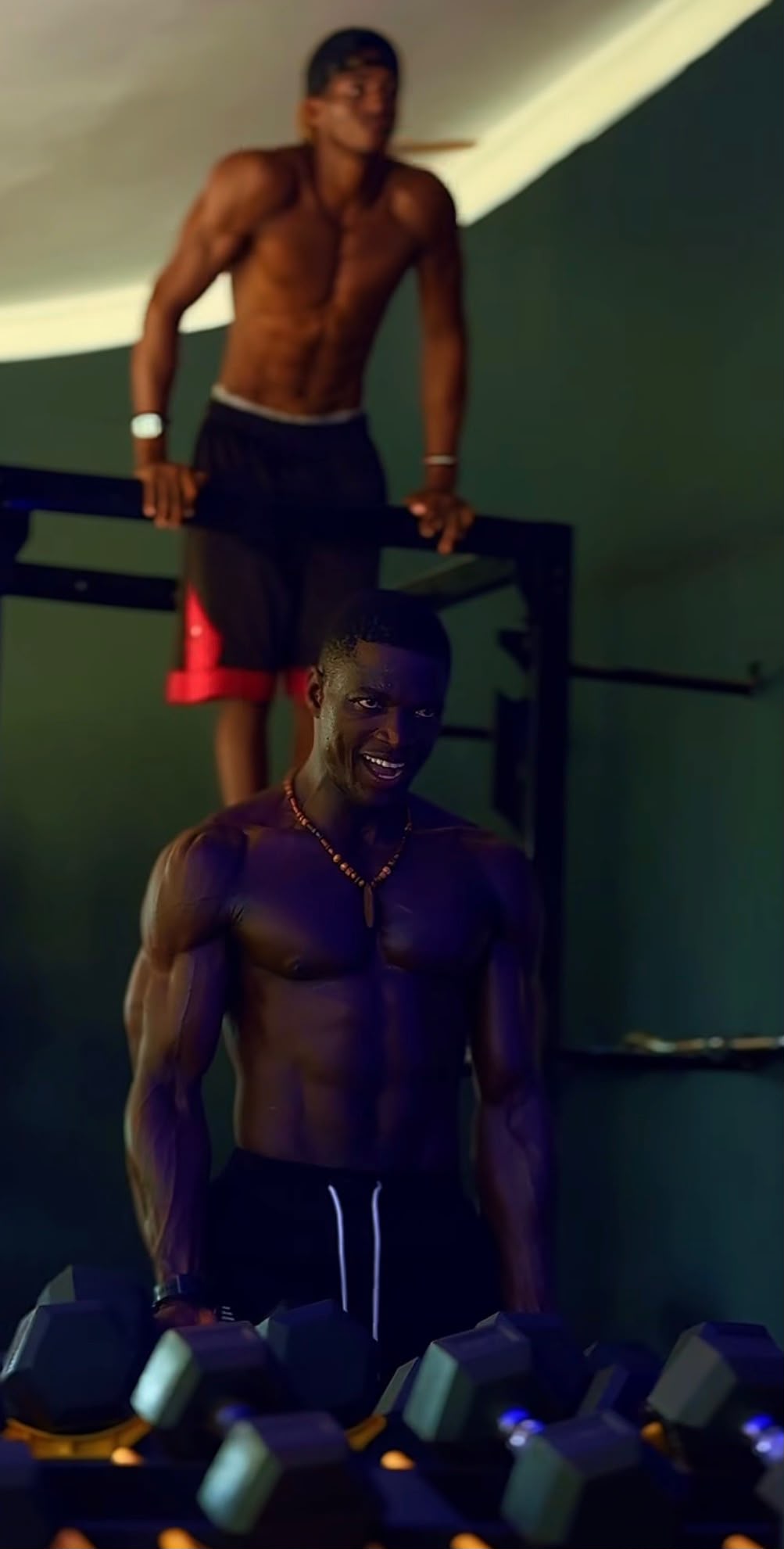 Two members training on the strength floor, one working the pull-up bar