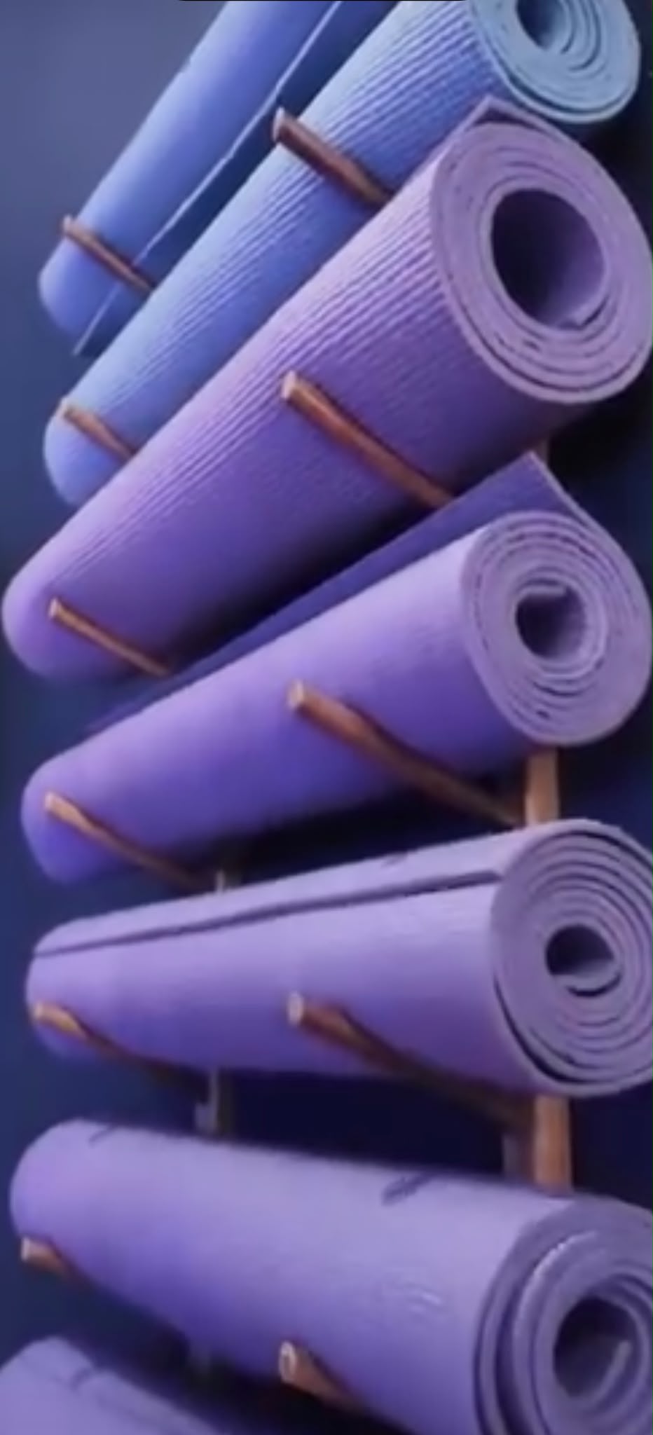 Rolled yoga mats stacked on the studio rack, ready for a class